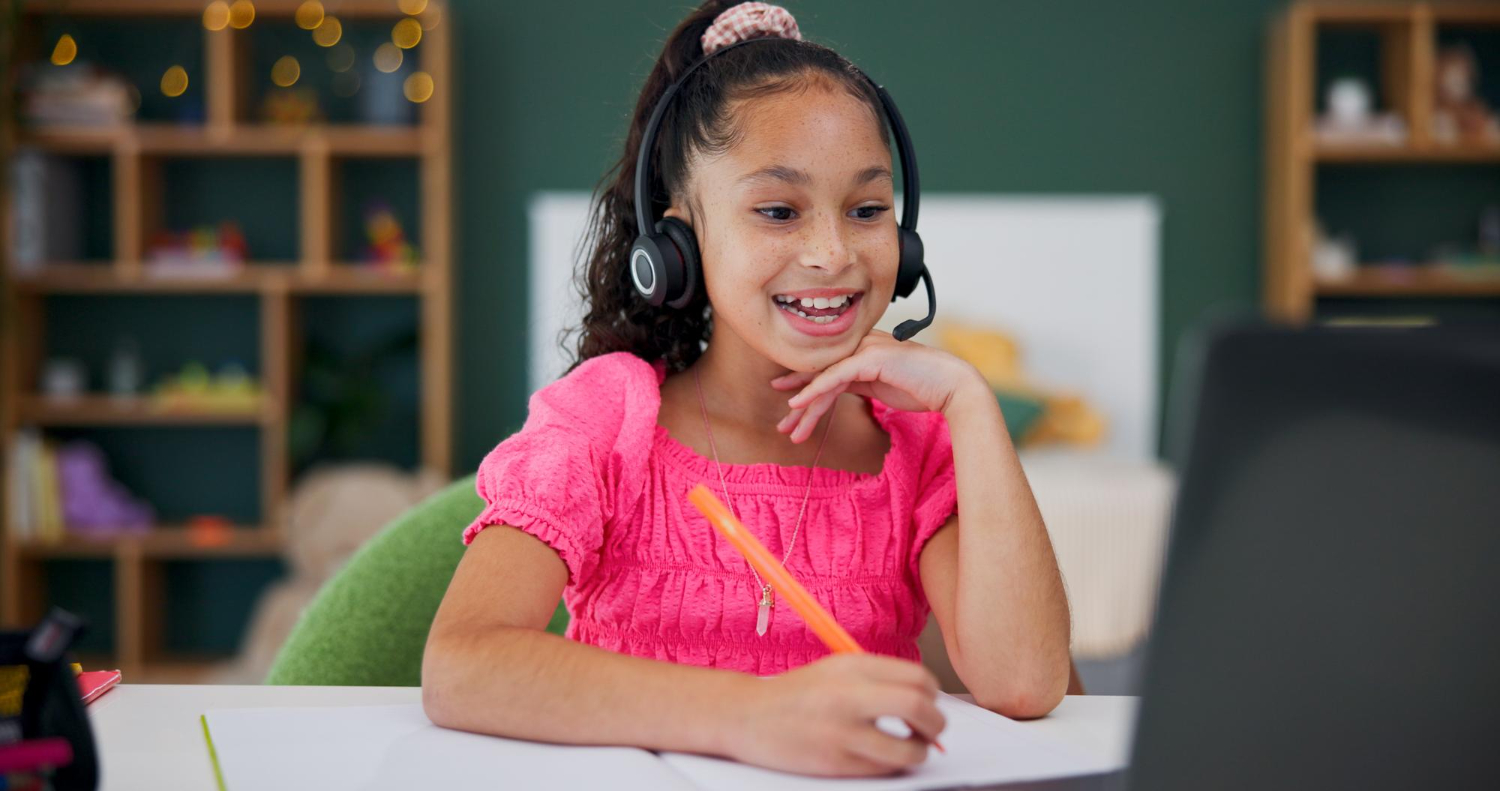 Young girl with headphones smiling during online elementary school class